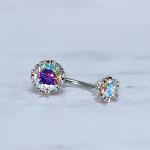 May include: A pair of silver body jewelry with iridescent gemstones. The larger gemstone is purple and the smaller gemstone is clear.