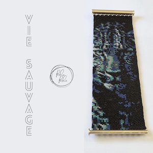 May include: A beaded bracelet with a black background and a pattern of blue, teal, and gray beads. The bracelet has gold-colored metal ends. The text "VIE SAUVAGE" is printed vertically on the left side of the image, and a logo that says "Perle Perle" is printed in a circle.