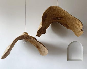 Pode incluir: Dois candeeiros pendentes de palha tecida pendurados no teto. Os candeeiros têm a forma de grandes chapéus flexíveis.