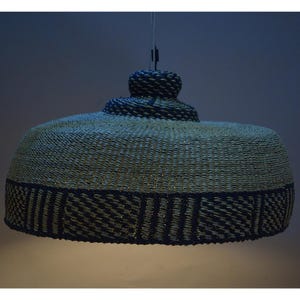 May include: A woven pendant light fixture with a black and white geometric pattern. The light fixture is made of natural materials and has a dome shape.