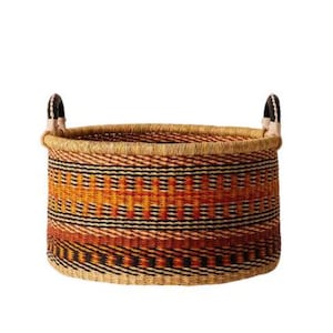 May include: A large, woven storage basket with black leather handles. The basket has a colorful geometric pattern in shades of orange, brown, and black.
