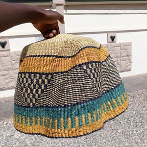 May include: A woven straw hat with a wide brim, featuring a colorful pattern of yellow, blue, and black stripes. The hat is made of natural materials and has a unique, handcrafted look.