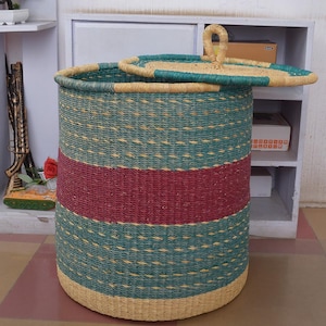 May include: A large, woven storage basket with a lid. The basket is made of natural materials and has a teal and burgundy striped pattern. The lid has a handle.
