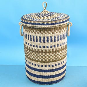 May include: A woven storage basket with a lid. The basket is made of natural materials and has a blue and brown geometric pattern. The lid has a handle on top.