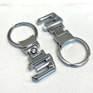 May include: Two silver keychains with a BMW logo. One keychain has the number "3" and the other has the number "5".
