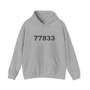 May include: A light gray hoodie with a front pocket and drawstring hood. The number "77833" is printed in dark gray across the chest. The hoodie is made of a soft, comfortable material.