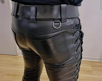 May include: Black leather pants with a belt and a silver D-ring. The pants have a classic five-pocket design and lace-up detailing on the sides. The belt is wide and made of the same black leather.