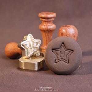 May include: A brass wax seal stamp featuring a star-shaped head with a wooden handle, accompanied by a circular brown wax impression displaying a star outline and the letter H in the center. Text at the bottom reads: Etsy Exclusive: TimelessByRitesia.etsy.com.