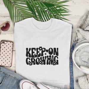 A camisa é motivacional, o moletom é inspirador, o suéter é edificante, a camiseta é reconfortante, continue crescendo, as flores são alegres, as letras são