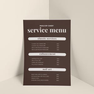 May include: A dark brown rectangular service menu sign with white text titled NAILS BY CASSY. The menu lists categories including classic services, enhancement, and nail art, with various service names and prices printed in a clean, sans-serif font.