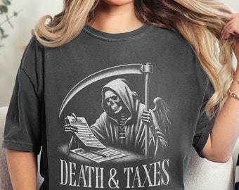 May include: Dark gray t-shirt featuring a black and white graphic of the Grim Reaper holding a scythe and reviewing a tax form. The words "DEATH & TAXES" are printed below the illustration. The shirt is a Pepper color.