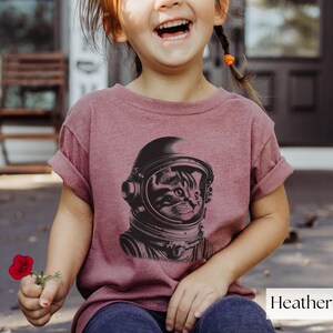 Adorable Space Cat Shirt featuring a cute kitty in an astronaut helmet, perfect for kids outer space birthday celebrations. This galaxy cat shirt makes a great gift for young space enthusiasts