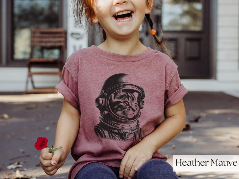 Adorable Space Cat Shirt featuring a cute kitty in an astronaut helmet, perfect for kids outer space birthday celebrations. This galaxy cat shirt makes a great gift for young space enthusiasts