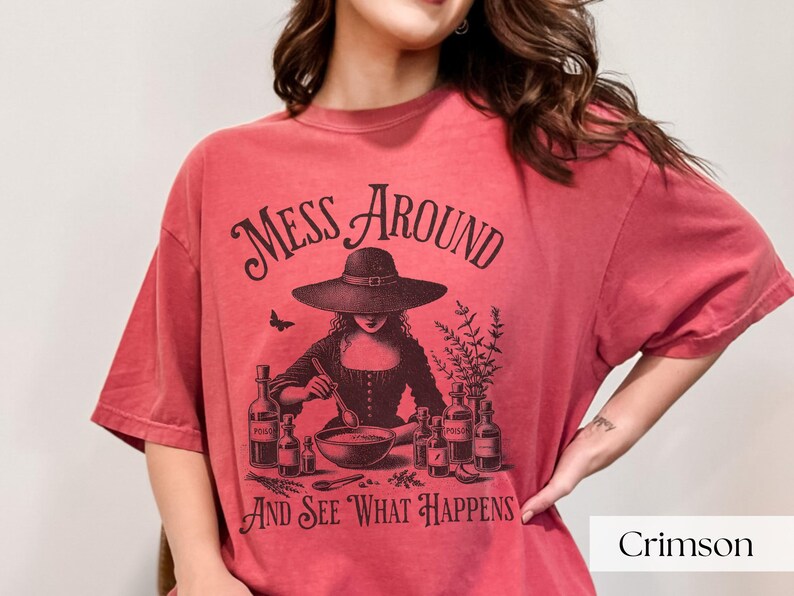 Woman wearing red Halloween Witch T-Shirt featuring Mess Around And See What Happens and a Witch Making Poison graphic. Perfect funny Halloween tee for a witchy aesthetic, spooky season, or a witch costume. Womens villain shirt for Halloween.