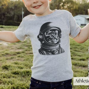 Adorable Space Cat Shirt featuring a cute kitty in an astronaut helmet, perfect for kids outer space birthday celebrations. This galaxy cat shirt makes a great gift for young space enthusiasts