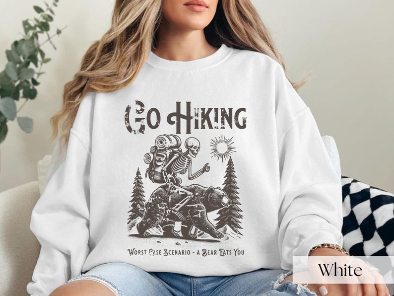 Woman wearing white Go Hiking Worst Case Scenario A Bear Kills You, Funny Camping Sweater featuring a skeleton on a bear. Perfect for outdoor enthusiasts and camper gifts. Ideal for Halloween and summer vacation.