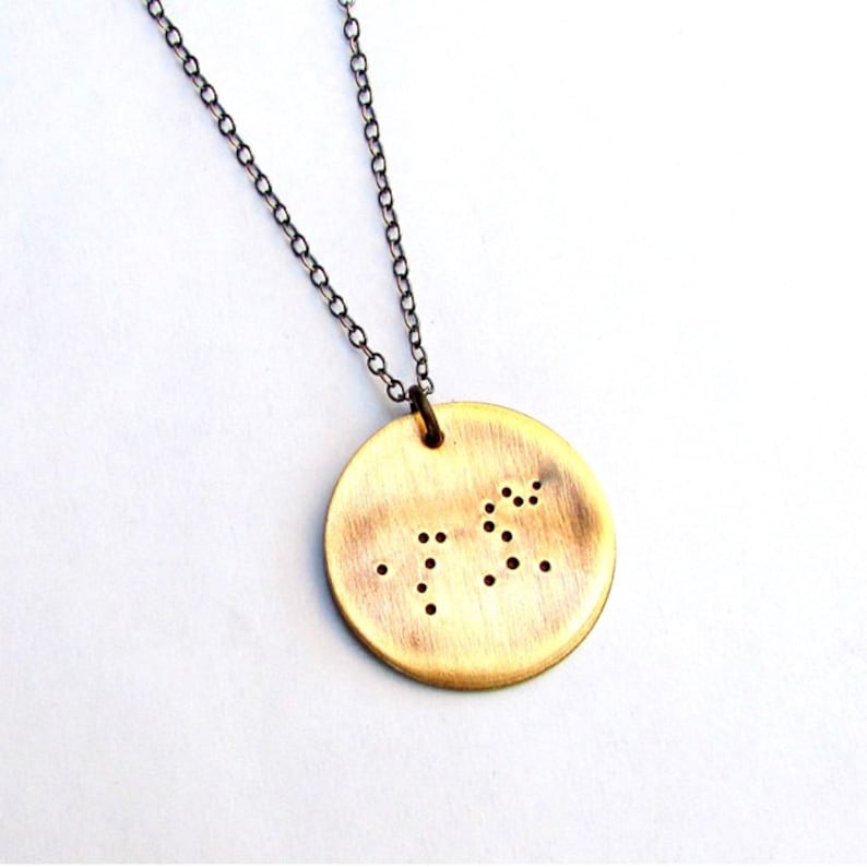 May include: A brass necklace with a round pendant featuring the number 72 in braille.