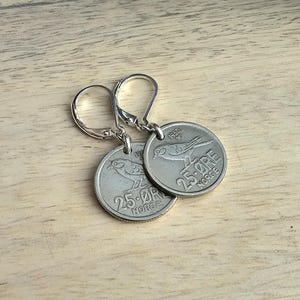 May include: A pair of silver earrings featuring vintage Norwegian 25 øre coins with a bird design. The coins are dated 1960 and feature the text "25 øre NORGE".