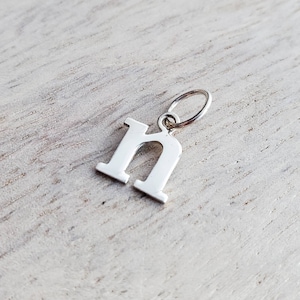 May include: Silver charm in the shape of the letter 'n'.
