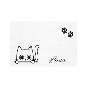 Peut inclure: Tapis de porte rectangulaire blanc avec un dessin au trait noir d'un chat regardant par-dessus une ligne, le nom "Luna" en cursive et deux empreintes de pattes. Le chat a de grands yeux ronds.