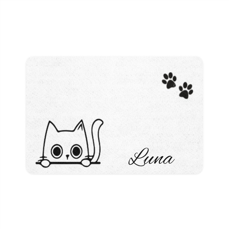 Peut inclure: Tapis de porte rectangulaire blanc avec un dessin au trait noir d'un chat regardant par-dessus une ligne, le nom "Luna" en cursive et deux empreintes de pattes. Le chat a de grands yeux ronds.