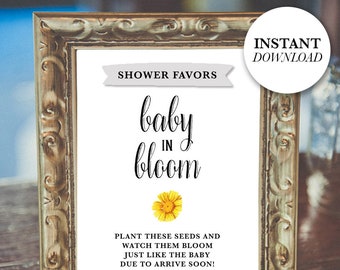 Op de afbeelding: Een ingelijst bord met de tekst "SHOWER FAVORS" en "baby in bloom". Het bord bevat een gele bloemafbeelding en de woorden "PLANT THESE SEEDS AND WATCH THEM BLOOM JUST LIKE THE BABY DUE TO ARRIVE SOON!" De woorden "INSTANT DOWNLOAD" staan in een witte cirkel.