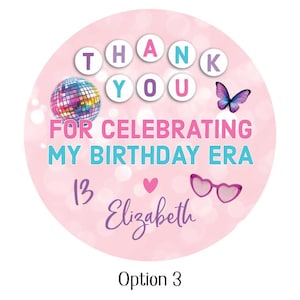 May include: A pink circular sticker with the words "THANK YOU" in white letters. The sticker also features a disco ball, butterfly, heart-shaped glasses, and the text "FOR CELEBRATING MY BIRTHDAY ERA 13 Elizabeth".