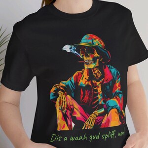 May include: A black t-shirt with a colorful graphic of a skeleton wearing a hat and smoking a cigarette. The text "Dis a waah gud spliff, mon!" is printed below the graphic.