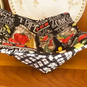 May include: Black and white fabric bowl with a checkered pattern on the bottom. The bowl is lined with a black fabric with a white print of various vegetables and spices, including onions, peppers, garlic, and tomatoes. The text on the fabric reads "4 RIP ATES 2 ONIONS 1/4 CUP 1/2 CUP FINED DICED CHOPPED PEPPRO".