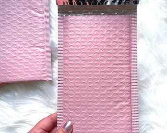 May include: Two pink bubble mailers with a silver and black patterned seal. The mailers are made of a soft, flexible material and have a padded interior to protect the contents.