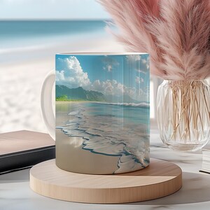 May include: White ceramic mug featuring a scenic beach view with blue water, white sand, and a bright sky. The mug is on a wooden coaster, with a vase of pink pampas grass and books in the background. The scene is set near a window.