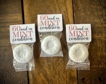 May include: Three white mint candies wrapped in clear plastic bags with pink and white labels that say "60 and in mint condition".