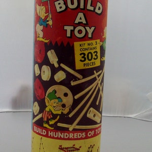 May include: A red and yellow vintage toy building kit in a round tin can. The can has a picture of a pixie holding a sign that says "Steven". The text on the can reads "Pixie Build A Toy Kit No. 3 Contains 303 Pieces". The can also has a picture of a pixie building a toy with the text "Build Hundreds of Toys Build Toys That Move... Swing."