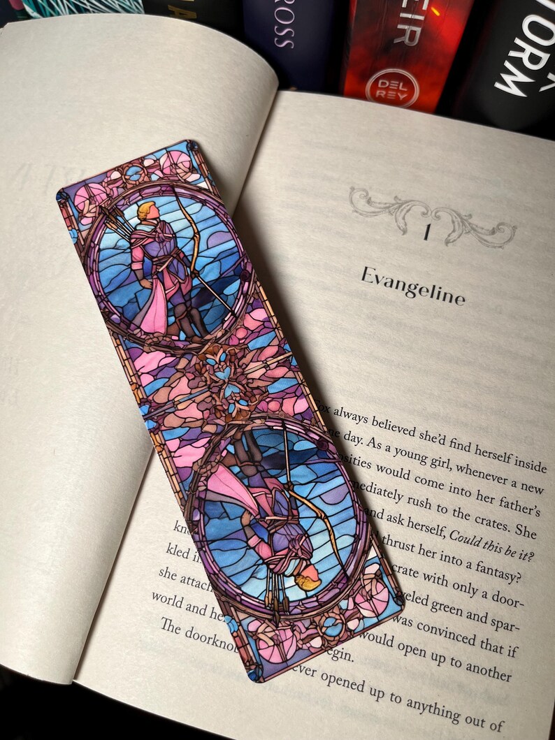 K&ouml;nnte beinhalten: Ein Lesezeichen aus Buntglas mit einem farbenfrohen Design einer Person, die einen Bogen und Pfeil h&auml;lt. Das Lesezeichen ist rechteckig und hat ein rosa, blaues und violettes Farbschema.