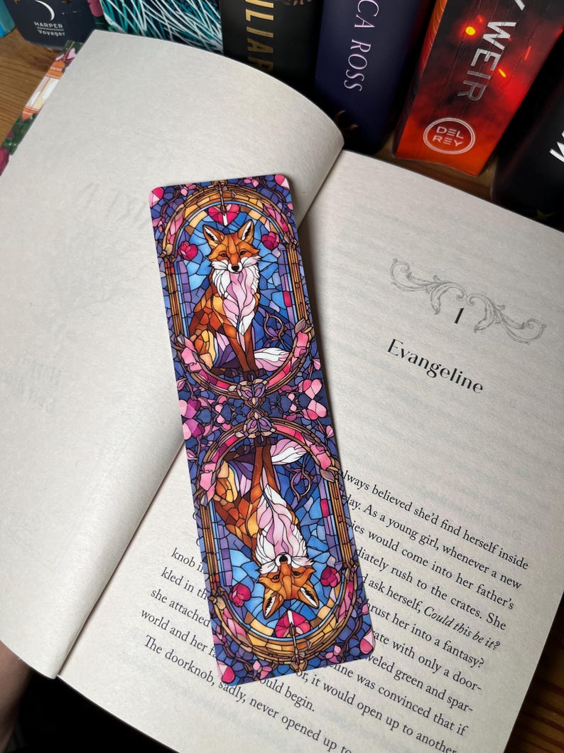 K&ouml;nnte beinhalten: Ein Lesezeichen mit einem Buntglasdesign von zwei F&uuml;chsen. Die F&uuml;chse sind in einer leuchtenden Farbpalette aus Rosa, Blau und Orange dargestellt. Das Lesezeichen ist rechteckig und hat eine gl&auml;nzende Oberfl&auml;che.