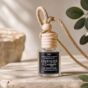 May include: A car air freshener with a black label that reads "Lavender & Eucalyptus." The clear glass bottle has a wooden top and a woven rope for hanging. The text on the label also says "Car Diffuser" and "8ml."