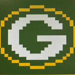 May include: Pixelated image of the Green Bay Packers logo. The logo features a white letter "G" inside a green oval, outlined in yellow. The background is a solid dark green.