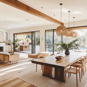 May include: A modern dining room with a large wooden table and chairs. The table is made of natural wood and has a rustic finish. The chairs are upholstered in a light brown fabric. The room has large windows that let in natural light. There are three wicker pendant lights hanging over the table.