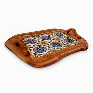 Op de afbeelding: Een houten serveerblad met een decoratief tegelinzetstuk. De lade is gemaakt van lichtbruin hout en heeft een rechthoekig tegelontwerp met blauwe bloempatronen. De lade heeft aan elk uiteinde een handvat.
