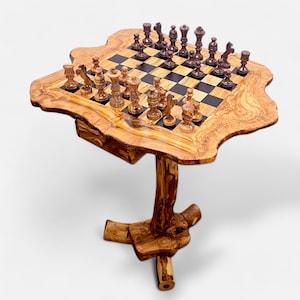 May include: A handcrafted wooden chess table with a unique, organic shape. The chess board features a black and tan checkered pattern, and the chess pieces are brown and tan. The table is supported by a single, natural-looking wooden leg.