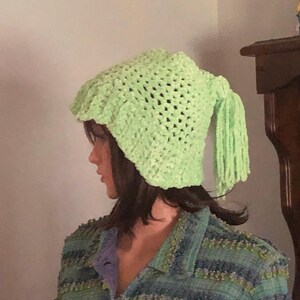 May include: A lime green crocheted hat with a long tassel. The hat is made with a simple stitch pattern and has a slouchy fit.