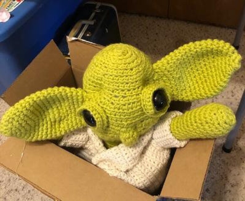 May include: A handmade crochet Yoda hat and costume in a cardboard box. The hat is lime green with large, pointed ears and black eyes. The costume includes a white crocheted top and sleeves.