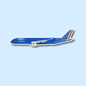 Puede incluir: Una pegatina azul y blanca de un avión de ITA Airways. El avión tiene el logotipo de ITA Airways en el lateral y la aleta de la cola presenta los colores de la bandera italiana. El fondo es de color azul claro.