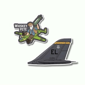 May include: Two stickers. One features a cartoon of a bearded man in a plane holding a bomb, with the text "Whiskey Pete." The other is a gray airplane tail with "EL" and "120" printed on it. The stickers have a white border.