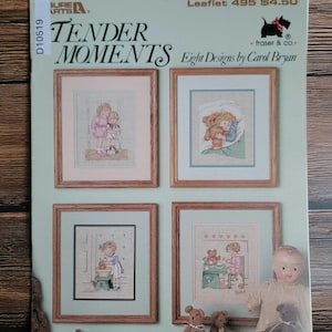 May include: A cross-stitch pattern leaflet titled "Tender Moments" by Carol Bryan. The cover features four framed cross-stitch designs with children and teddy bears. The leaflet includes a doll, shoes, and teddy bears.