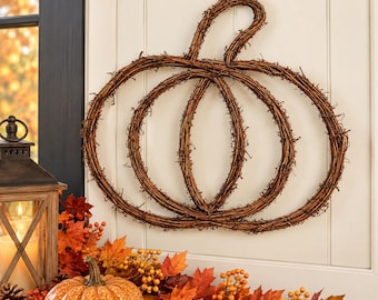 May include: A wall-mounted pumpkin-shaped decoration crafted from brown intertwined twigs and branches. The structure features a central oval shape flanked by two larger curved sections, topped with a single looped stem made of the same material.