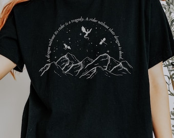 May include: Black t-shirt with a white graphic of mountains, stars, and dragons. The text on the shirt reads "A dragon without its rider is a tragedy. A rider without their dragon is dead."