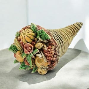 以下が含まれることがあります： かぼちゃ、りんご、ぶどう、ベリーなど、さまざまな果物や野菜で満たされたセラミック製の豊穣の角。豊穣の角は、豊かさと繁栄の伝統的なシンボルです。