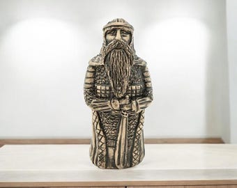 May include: A ceramic statue of a warrior with a long beard and a sword. The statue is painted in shades of brown and gold.