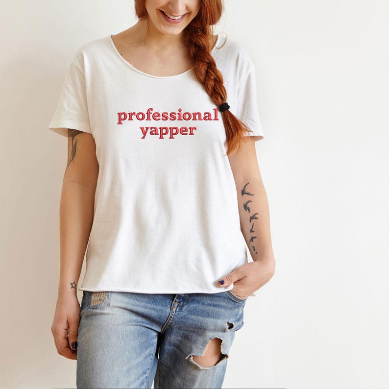 May include: White t-shirt with the text "professional yapper" in red lettering.
